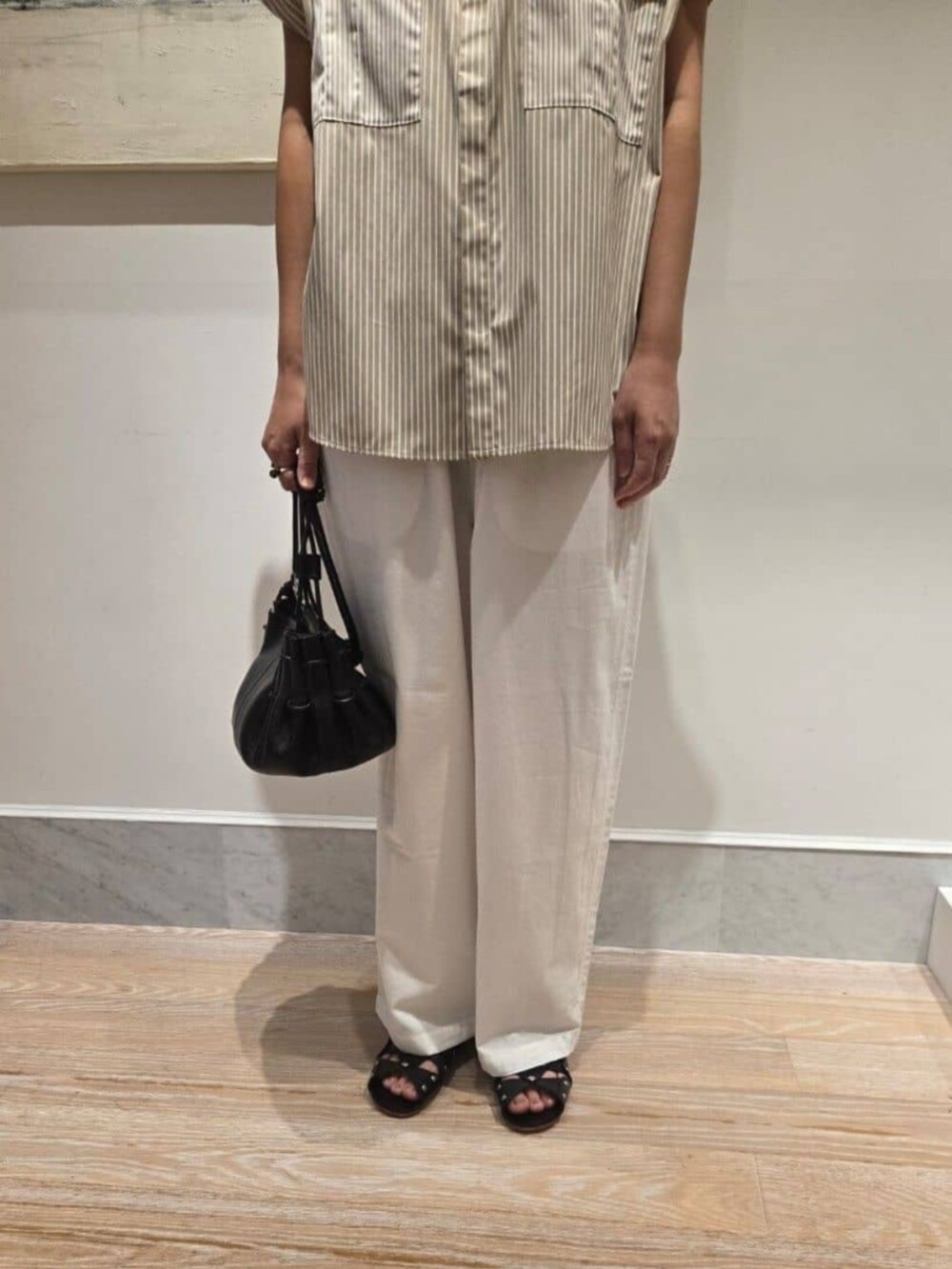 ベージュ系のシャツ/ブラウス、ホワイト系のその他パンツ、ブラック系のハンドバッグを着用したレディースの夏コーディネートの6枚目の写真