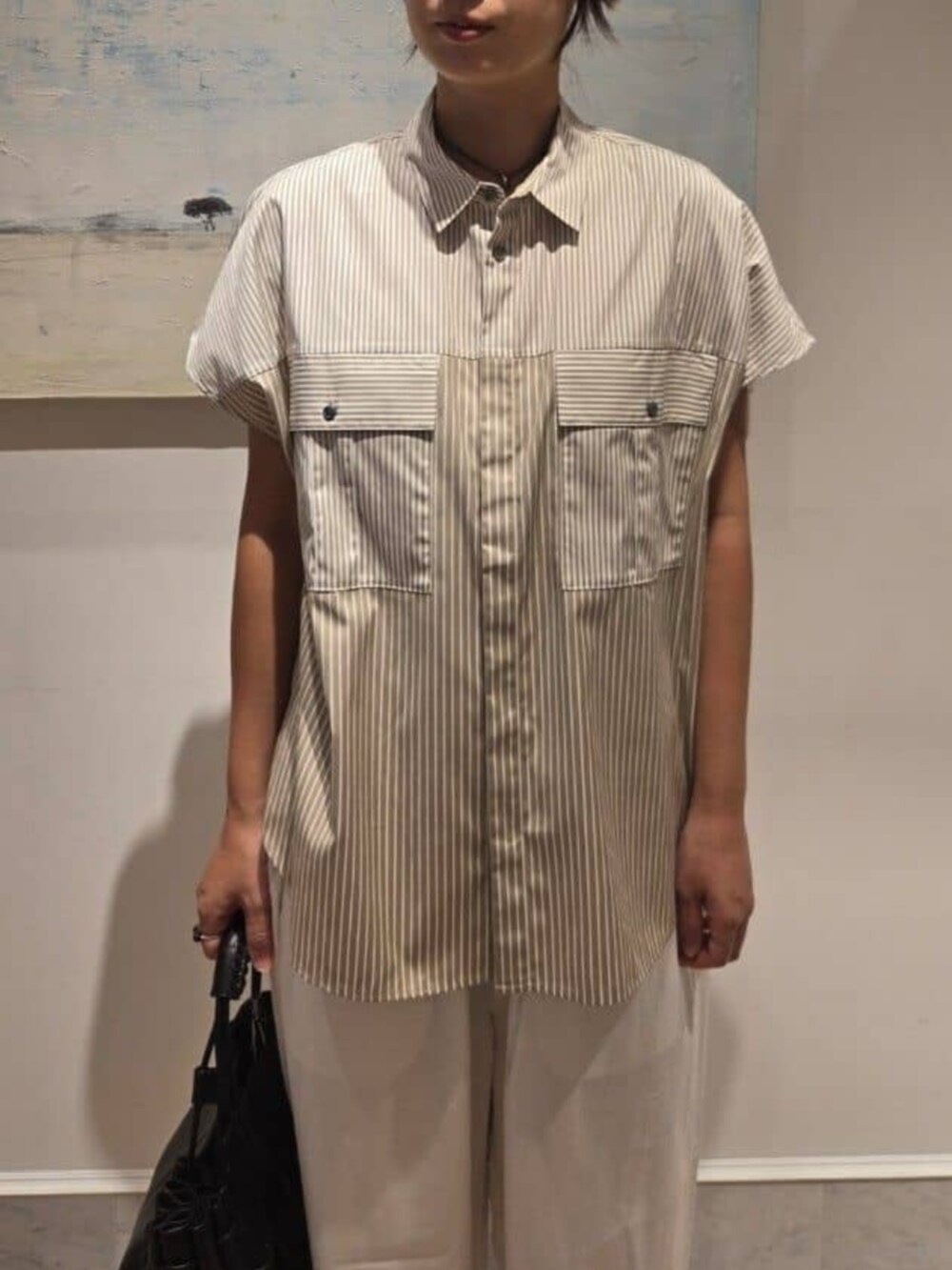 ベージュ系のシャツ/ブラウス、ホワイト系のその他パンツ、ブラック系のハンドバッグを着用したレディースの夏コーディネートの4枚目の写真