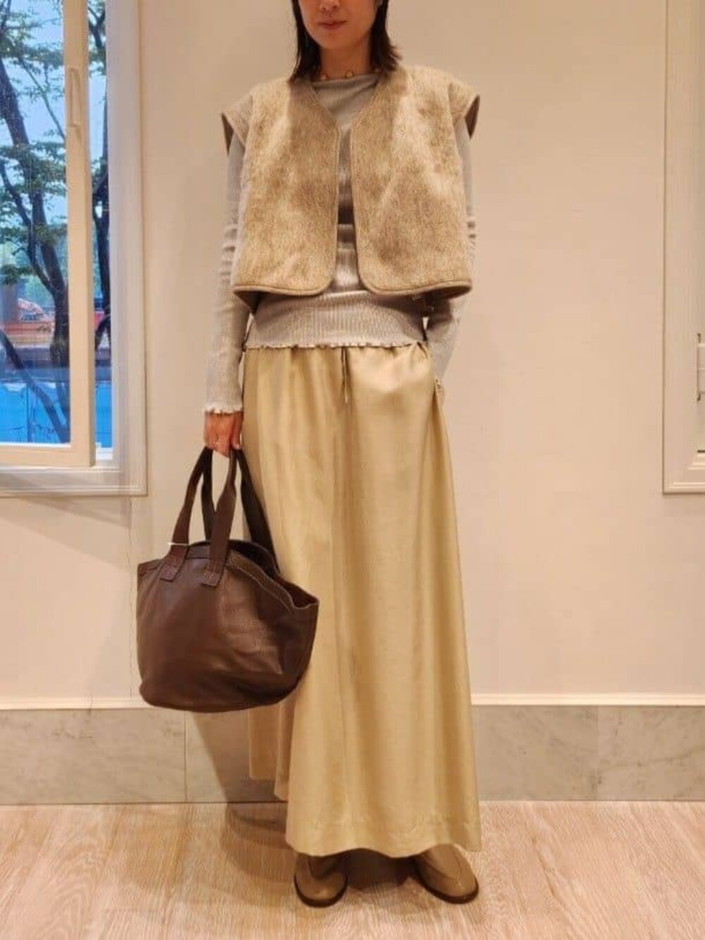 グレー系のブーツ、ベージュ系のベスト、グレー系のTシャツ/カットソーを着用したレディースの秋コーディネートの2枚目の写真