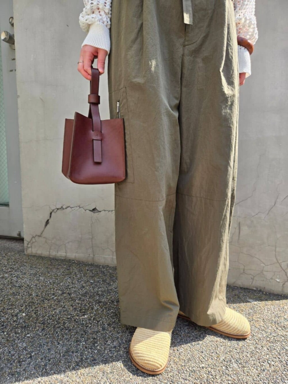 ホワイト系のパーカー、グリーン系のその他パンツ、ブラウン系のハンドバッグを着用したレディースの春コーディネートの3枚目の写真