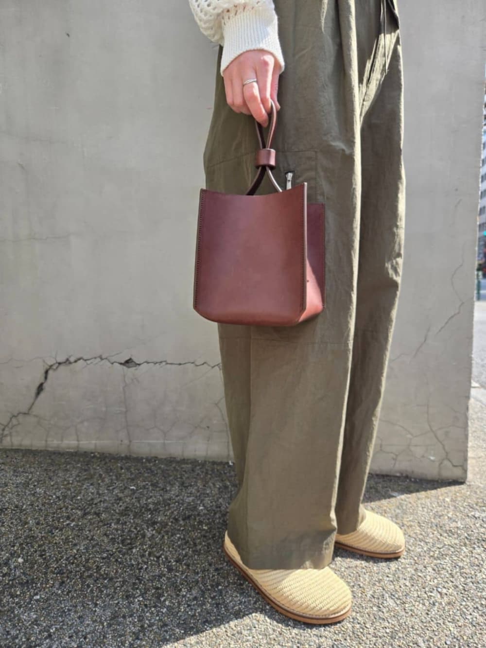 ホワイト系のパーカー、グリーン系のその他パンツ、ブラウン系のハンドバッグを着用したレディースの春コーディネートの4枚目の写真