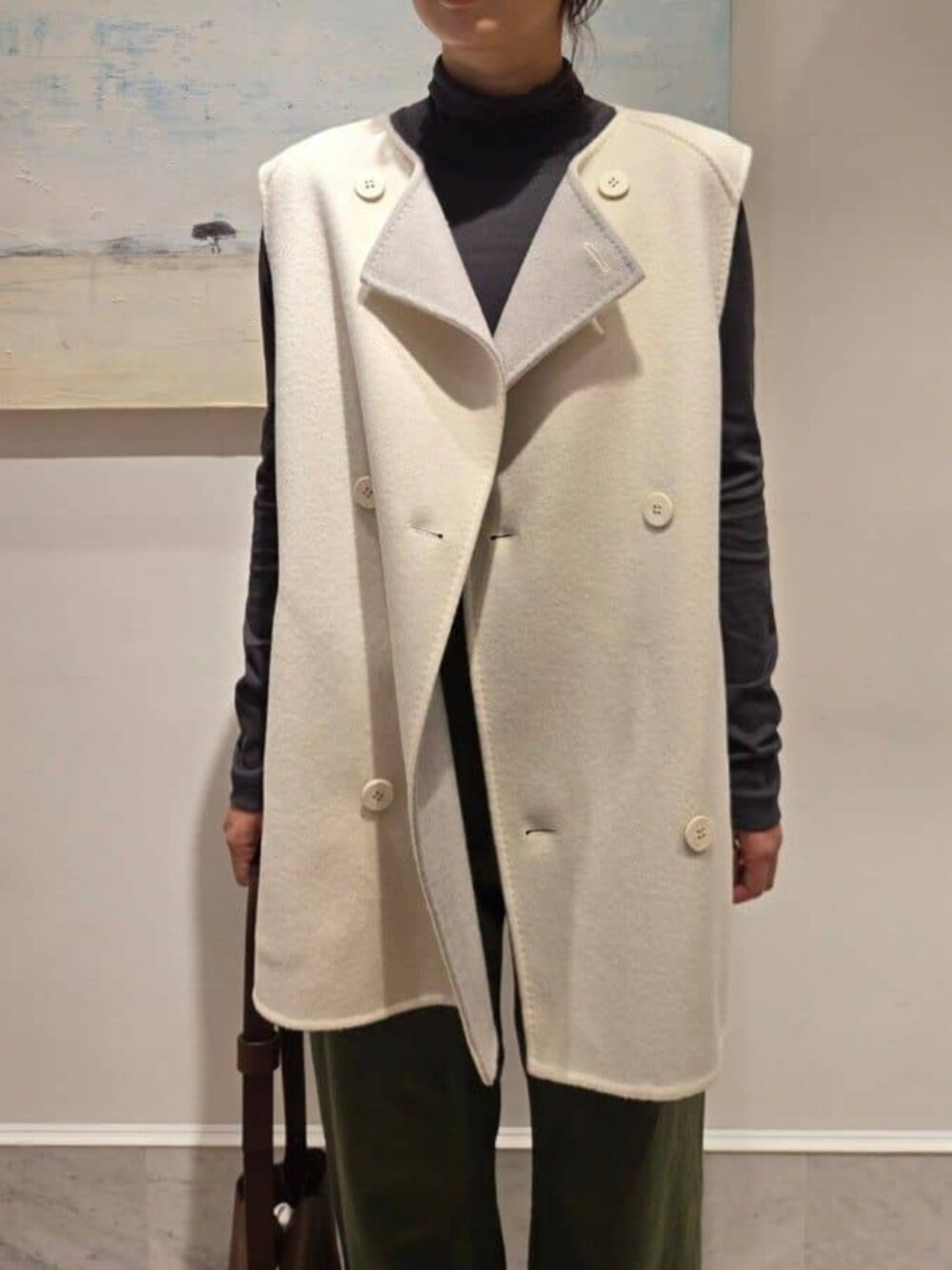 ホワイト系のベスト、グレー系のTシャツ/カットソー、ブラウン系のショルダーバッグを着用したレディースの秋コーディネートの2枚目の写真