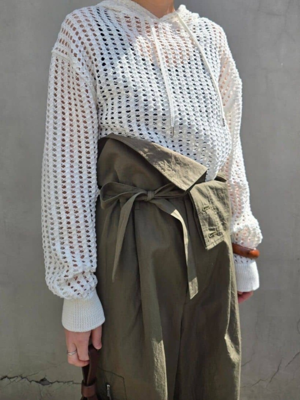 ホワイト系のパーカー、グリーン系のその他パンツ、ブラウン系のハンドバッグを着用したレディースの春コーディネートの2枚目の写真