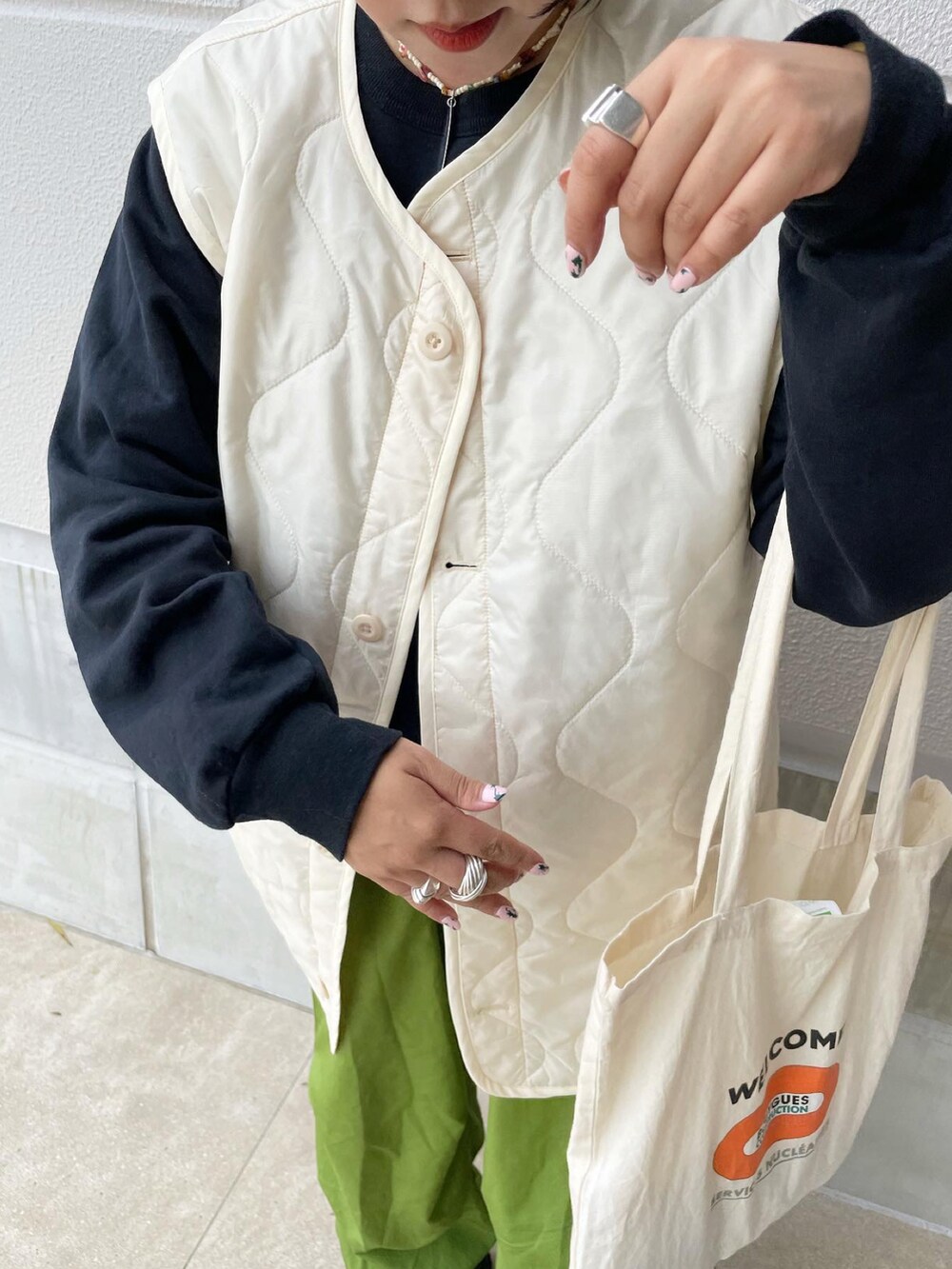 ホワイト系のナイロンジャケット、グリーン系のパンツ、ブラック系のスニーカーを着用したレディースの秋コーディネートの5枚目の写真