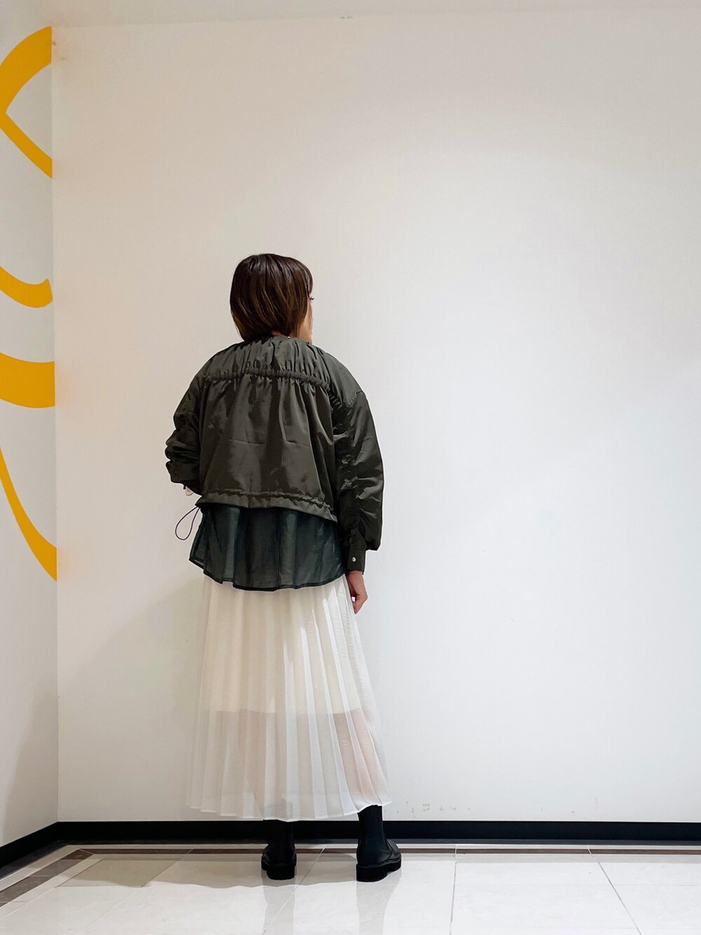 ホワイト系のニット/セーター、ホワイト系のスカート、グリーン系のブルゾンを着用したレディースの秋コーディネートの2枚目の写真