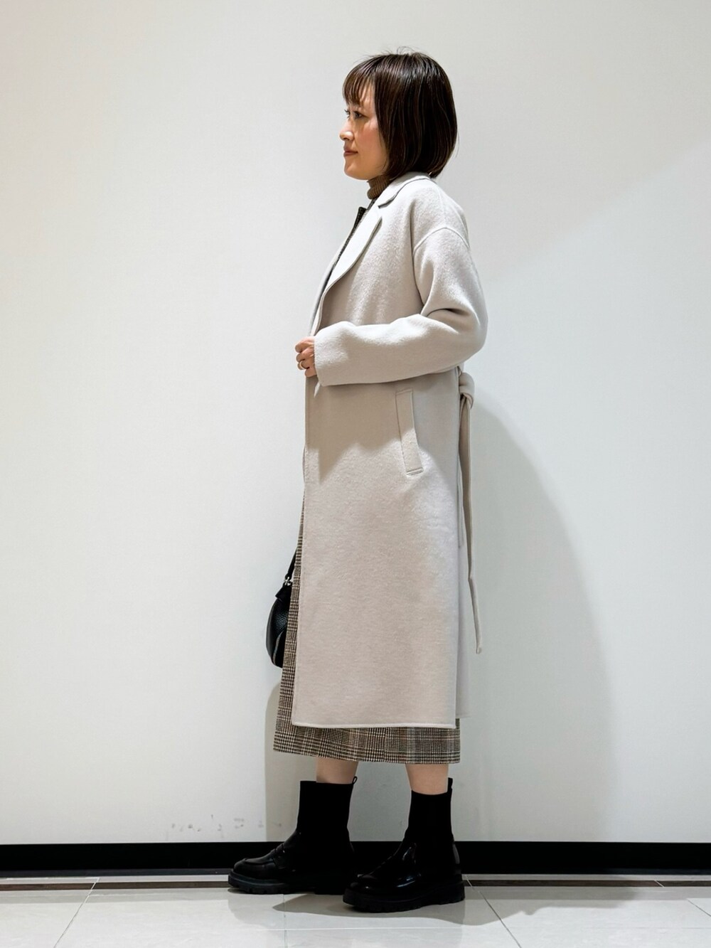 ホワイト系のチェスターコート、ブラウン系のワンピース、ブラウン系のニット/セーターを着用したレディースの冬コーディネートの4枚目の写真