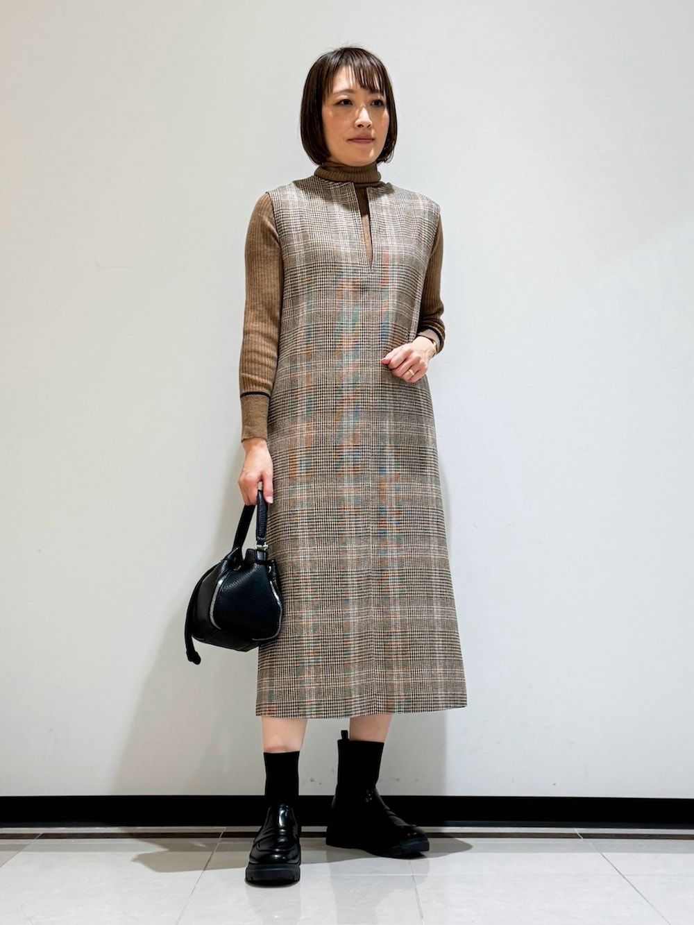 ホワイト系のチェスターコート、ブラウン系のワンピース、ブラウン系のニット/セーターを着用したレディースの冬コーディネートの5枚目の写真