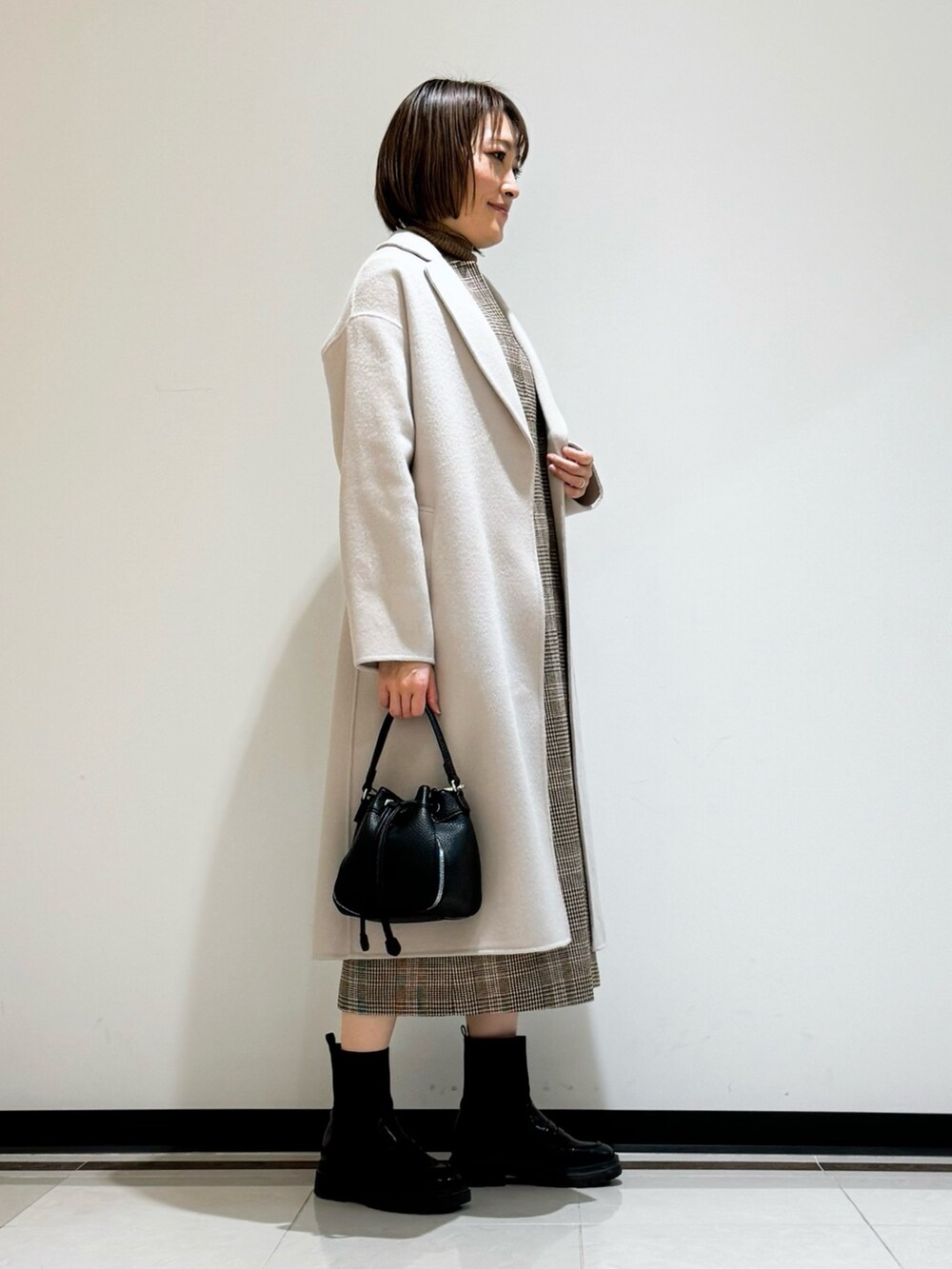 ホワイト系のチェスターコート、ブラウン系のワンピース、ブラウン系のニット/セーターを着用したレディースの冬コーディネートの2枚目の写真