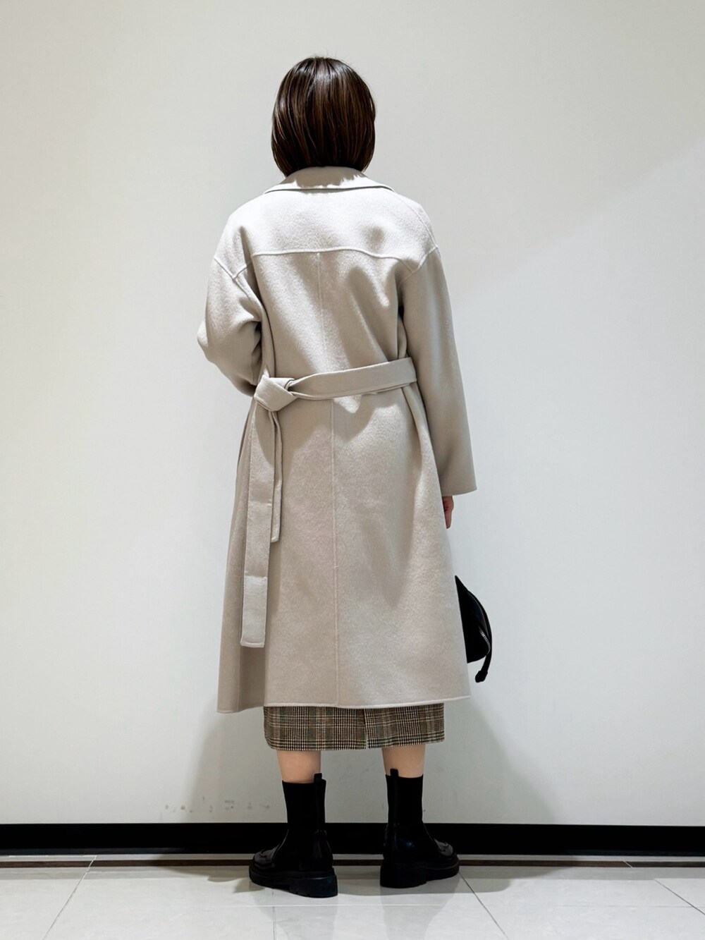 ホワイト系のチェスターコート、ブラウン系のワンピース、ブラウン系のニット/セーターを着用したレディースの冬コーディネートの3枚目の写真