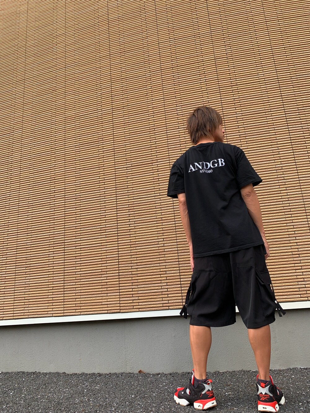 ホワイト系のスニーカー、ブラック系のTシャツ/カットソー、ブラック系のカーゴパンツを着用したメンズの秋コーディネートの2枚目の写真