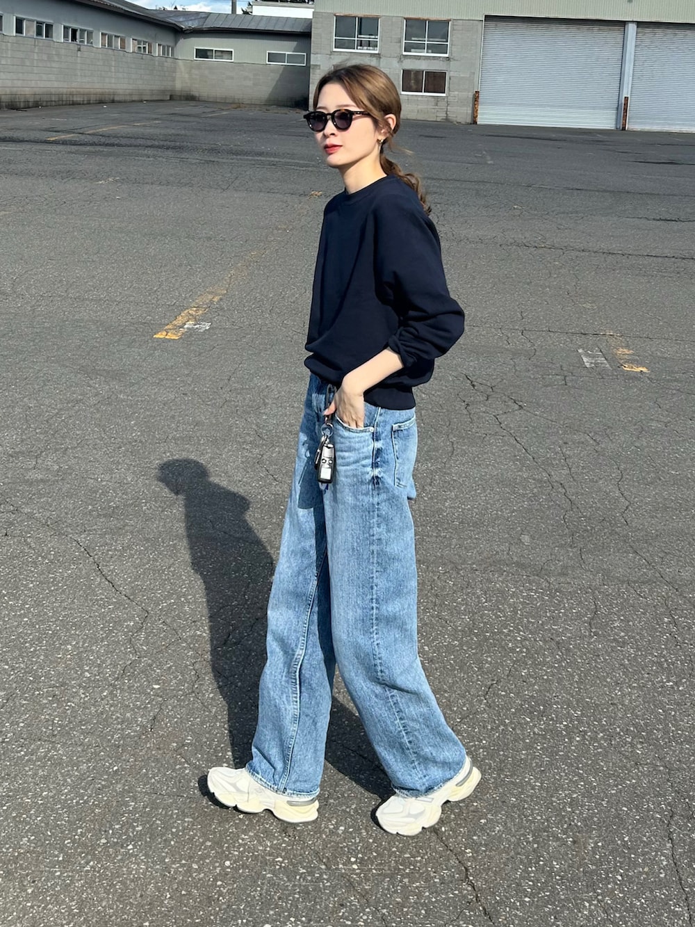 ブルー系のデニムパンツ、ブルー系のスウェット、ホワイト系のスニーカーを着用したレディースの秋コーディネートの2枚目の写真