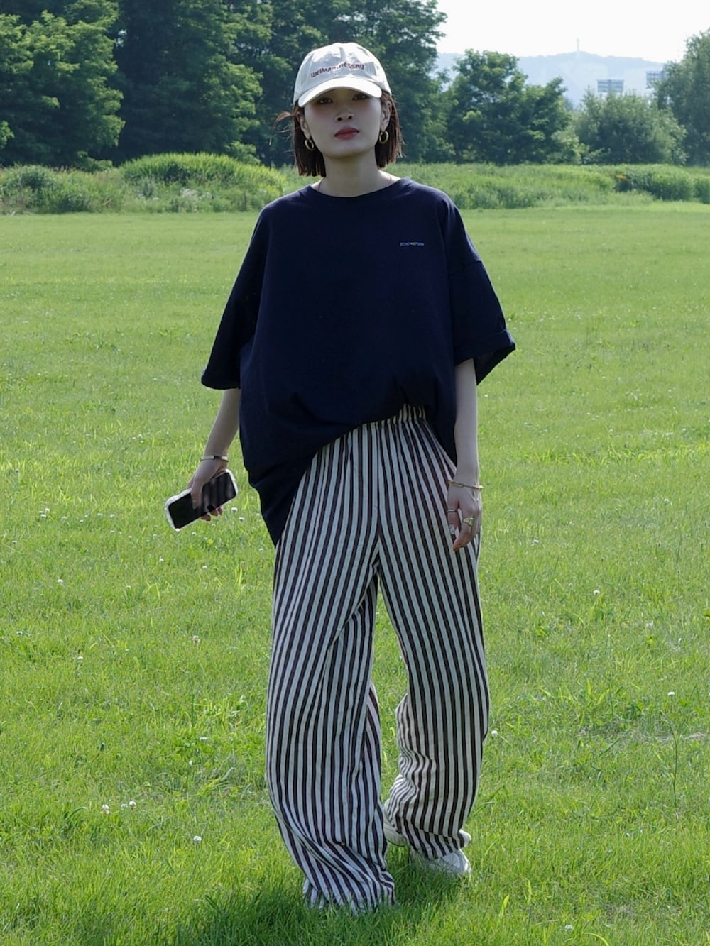 ブルー系のTシャツ/カットソー、ホワイト系のスニーカー、ホワイト系のキャップを着用したレディースの夏コーディネートの2枚目の写真