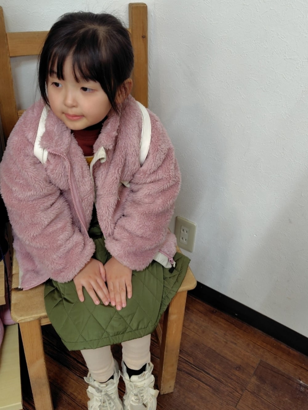 ピンク系のブルゾン、グリーン系のジャンパースカート、レッド系のスウェットを着用したキッズの冬コーディネートの2枚目の写真