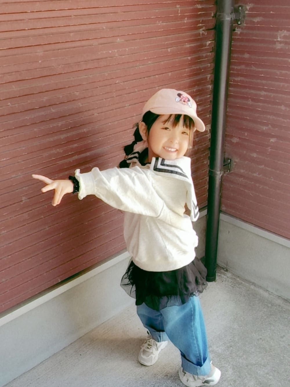 ベージュ系のスウェット、ブラック系のスカート、ブルー系のデニムパンツを着用したキッズの秋コーディネートの2枚目の写真