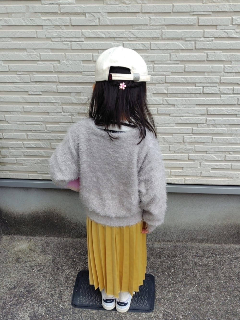 ベージュ系のカーディガン/ボレロ、ホワイト系のTシャツ/カットソー、イエロー系のスカートを着用したキッズの春コーディネートの3枚目の写真