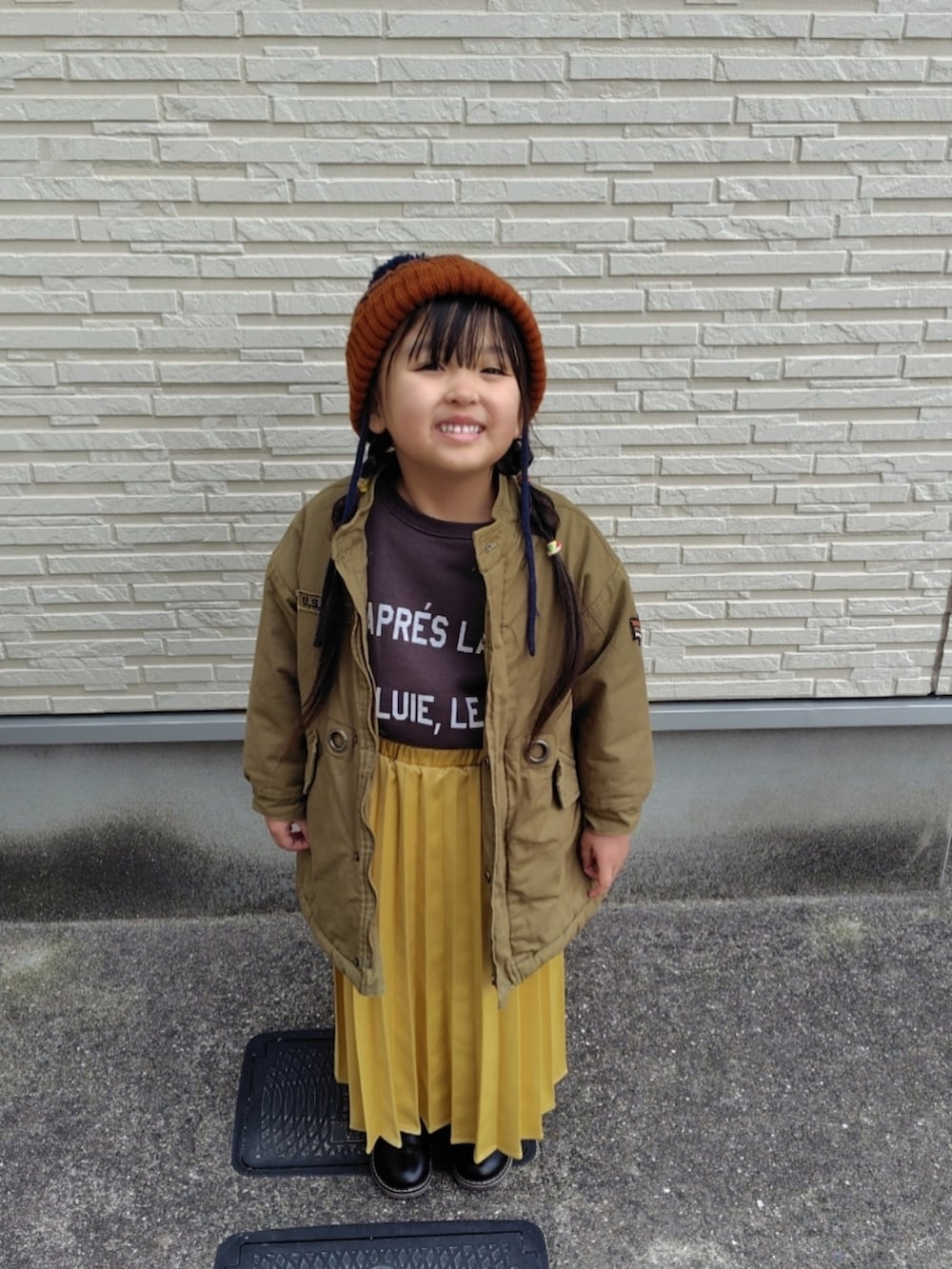 グリーン系のミリタリージャケット、グレー系のスウェット、イエロー系のスカートを着用したキッズの冬コーディネートの3枚目の写真