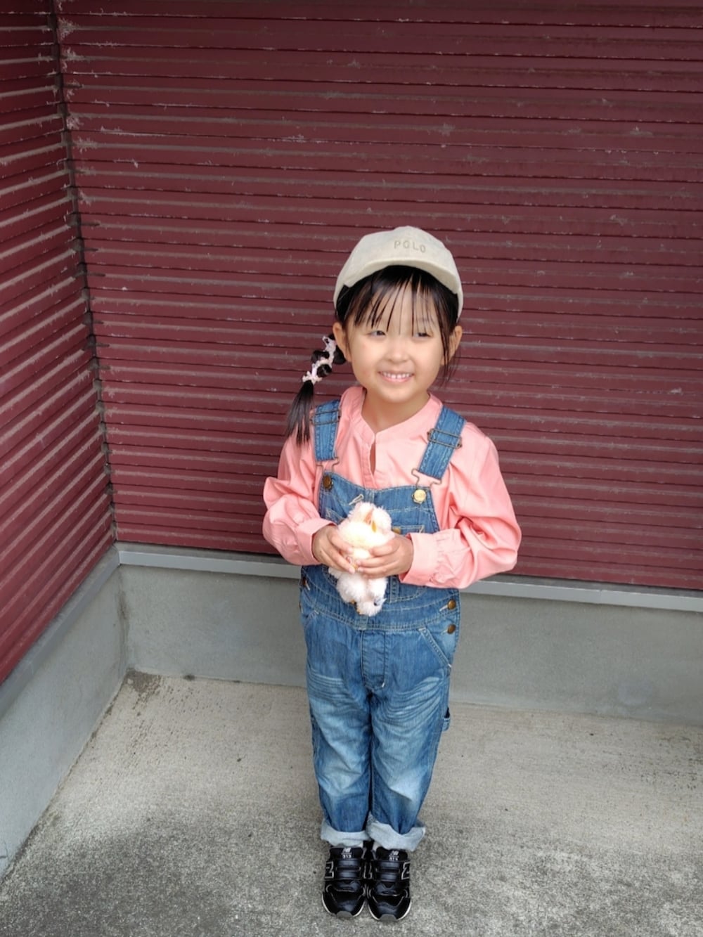 ブルー系のサロペット/オーバーオール、ピンク系のシャツ/ブラウス、ブラック系のスニーカーを着用したキッズの春コーディネートの2枚目の写真