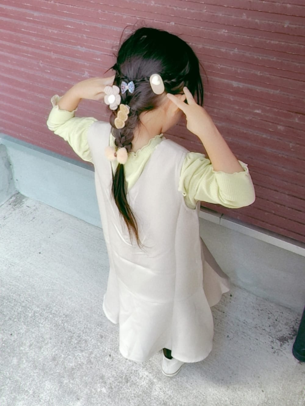 ベージュ系のジャンパースカート、グリーン系のTシャツ/カットソー、ホワイト系のスニーカーを着用したキッズの秋コーディネートの2枚目の写真