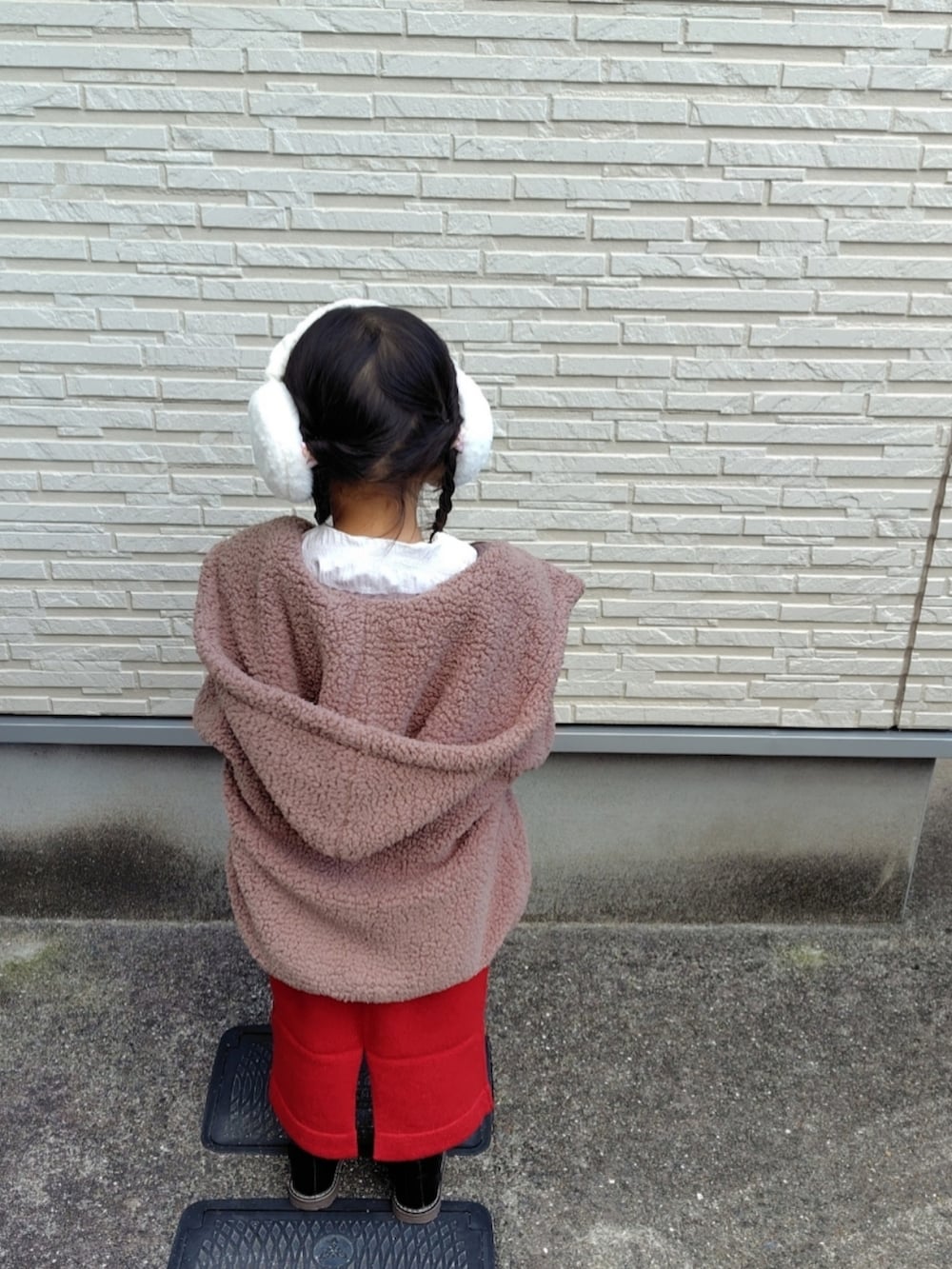 ブラウン系のブルゾン、レッド系のワンピース、ホワイト系のTシャツ/カットソーを着用したキッズの冬コーディネートの3枚目の写真