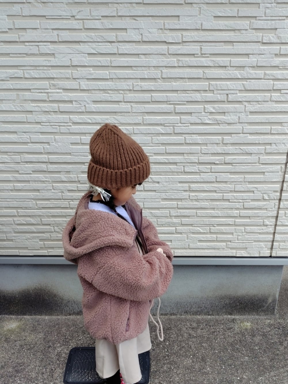 ブラウン系のブルゾン、パープル系のニット/セーター、ベージュ系のジャンパースカートを着用したキッズの冬コーディネートの4枚目の写真