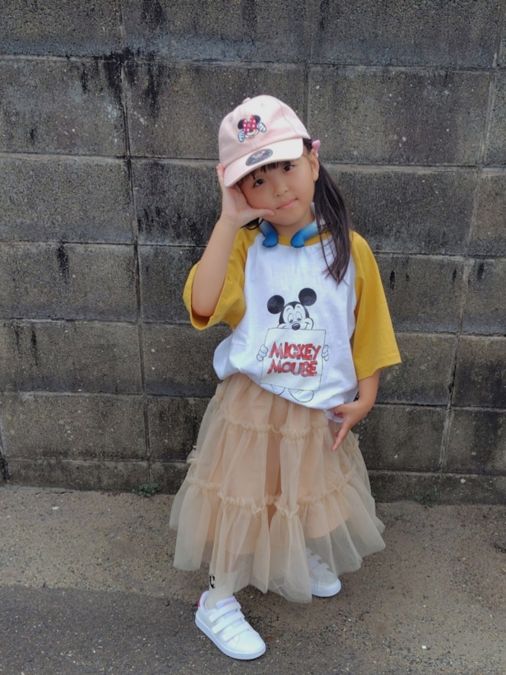 イエロー系のTシャツ/カットソー、ベージュ系のスカート、ホワイト系のスニーカーを着用したキッズの夏コーディネートの2枚目の写真