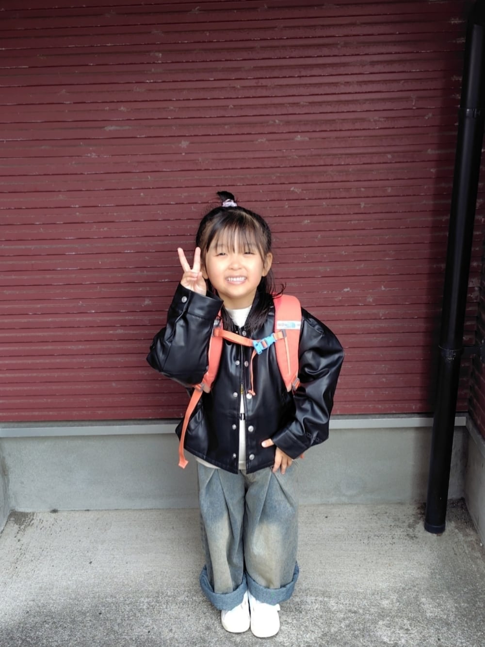 ブラック系のブルゾン、ベージュ系のスウェット、ブルー系のデニムパンツを着用したキッズの春コーディネートの2枚目の写真