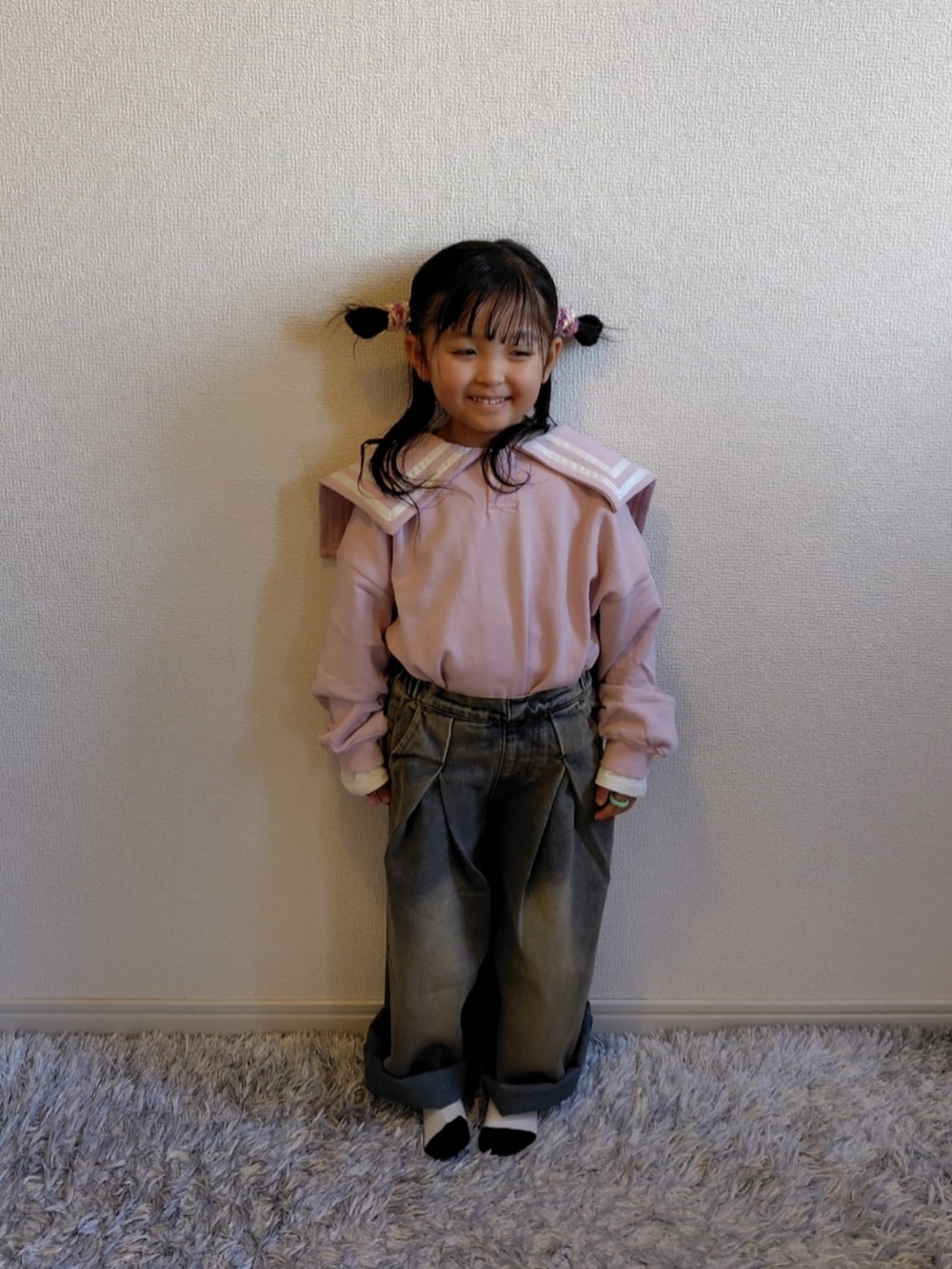 ピンク系のスウェット、ブルー系のデニムパンツ、ホワイト系のスニーカーを着用したキッズの冬コーディネートの2枚目の写真