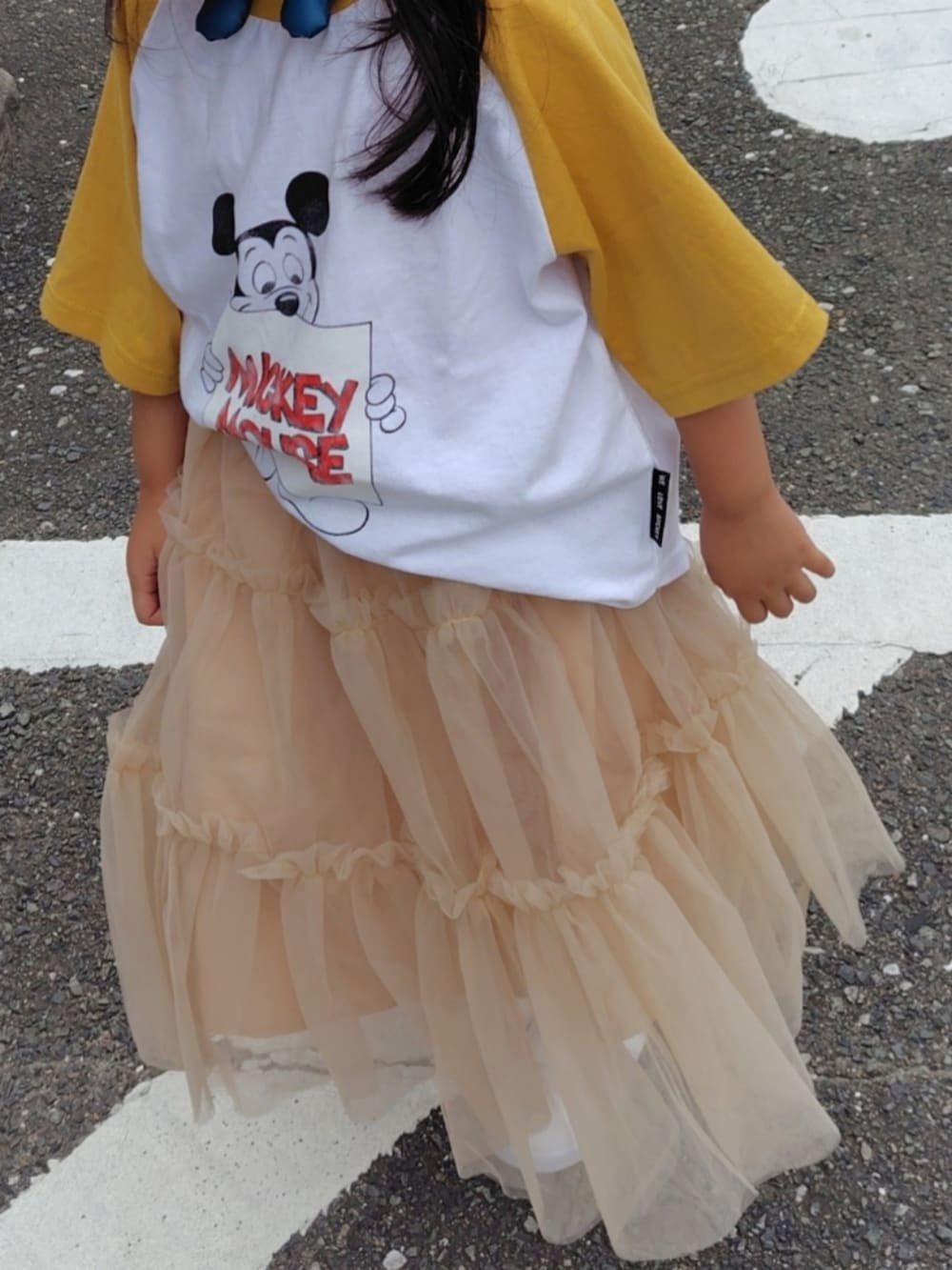 イエロー系のTシャツ/カットソー、ベージュ系のスカート、ホワイト系のスニーカーを着用したキッズの夏コーディネートの3枚目の写真