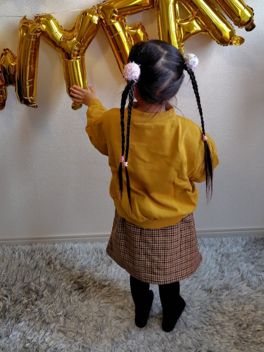 イエロー系のスウェット、ベージュ系のスカートを着用したキッズの冬コーディネートの2枚目の写真
