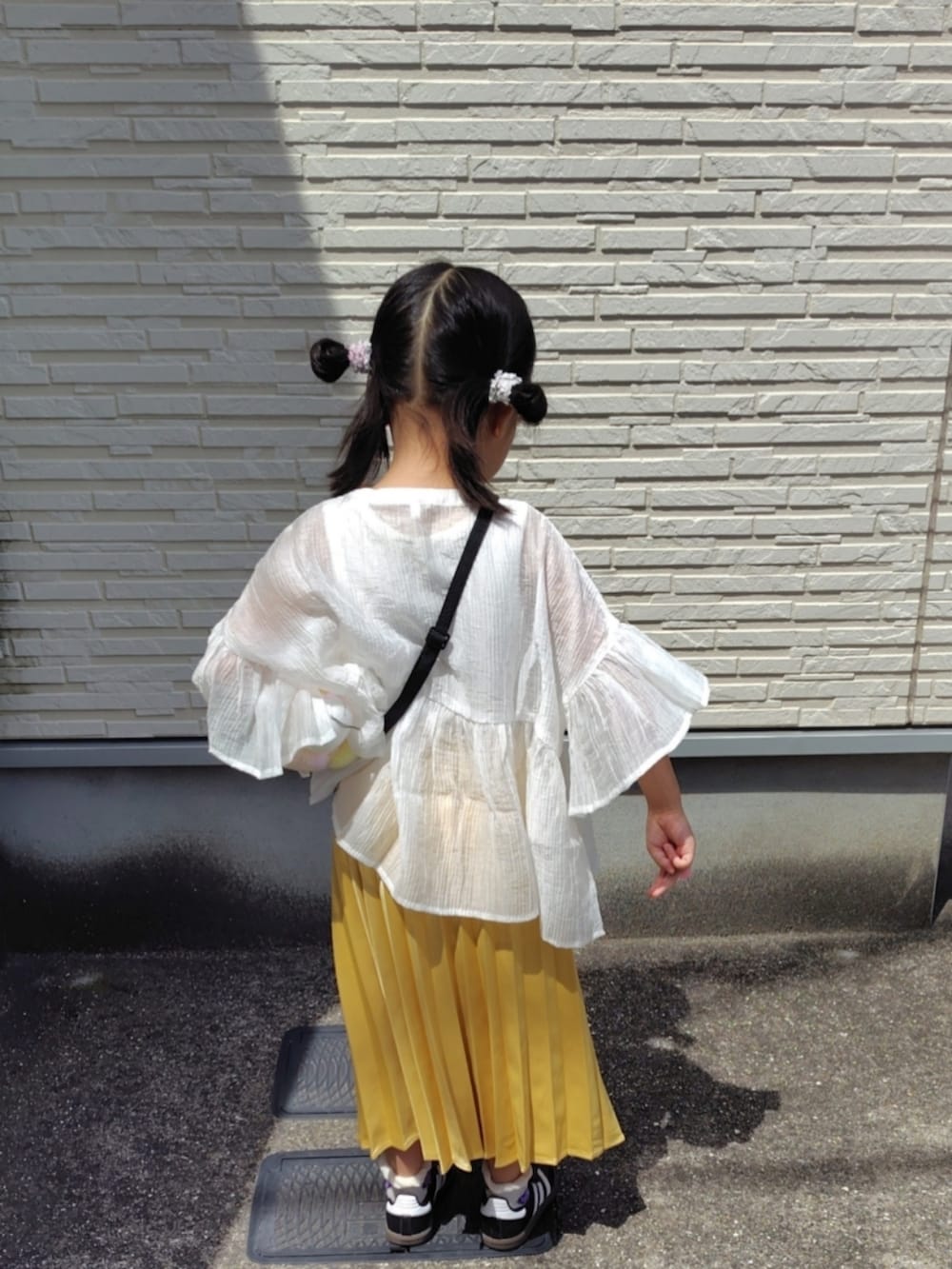 ホワイト系のシャツ/ブラウス、イエロー系のスカート、ブラック系のスニーカーを着用したキッズの夏コーディネートの4枚目の写真