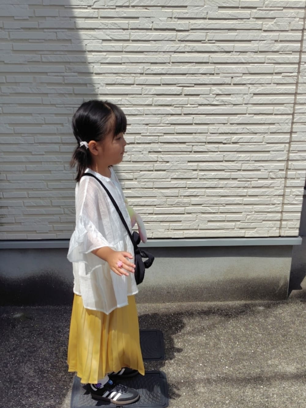 ホワイト系のシャツ/ブラウス、イエロー系のスカート、ブラック系のスニーカーを着用したキッズの夏コーディネートの3枚目の写真