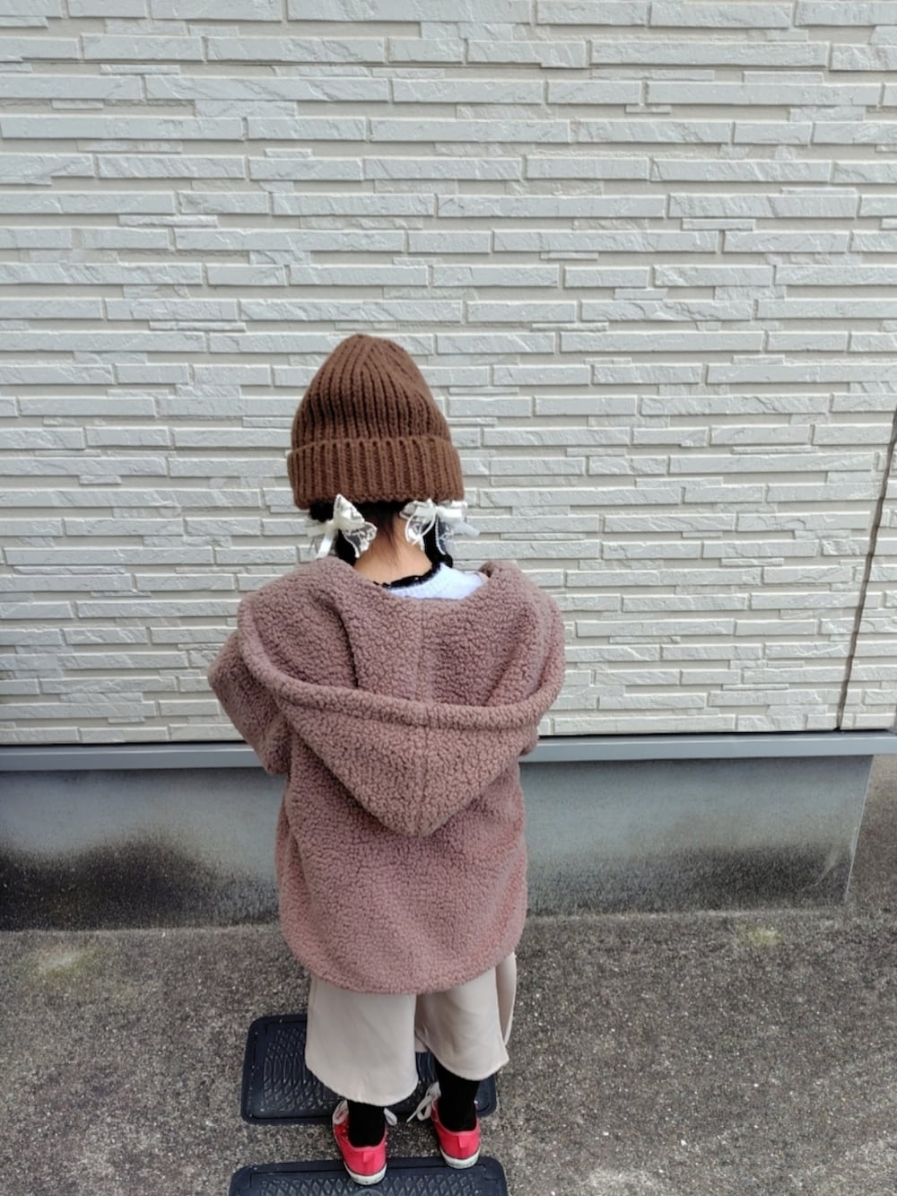 ブラウン系のブルゾン、パープル系のニット/セーター、ベージュ系のジャンパースカートを着用したキッズの冬コーディネートの2枚目の写真