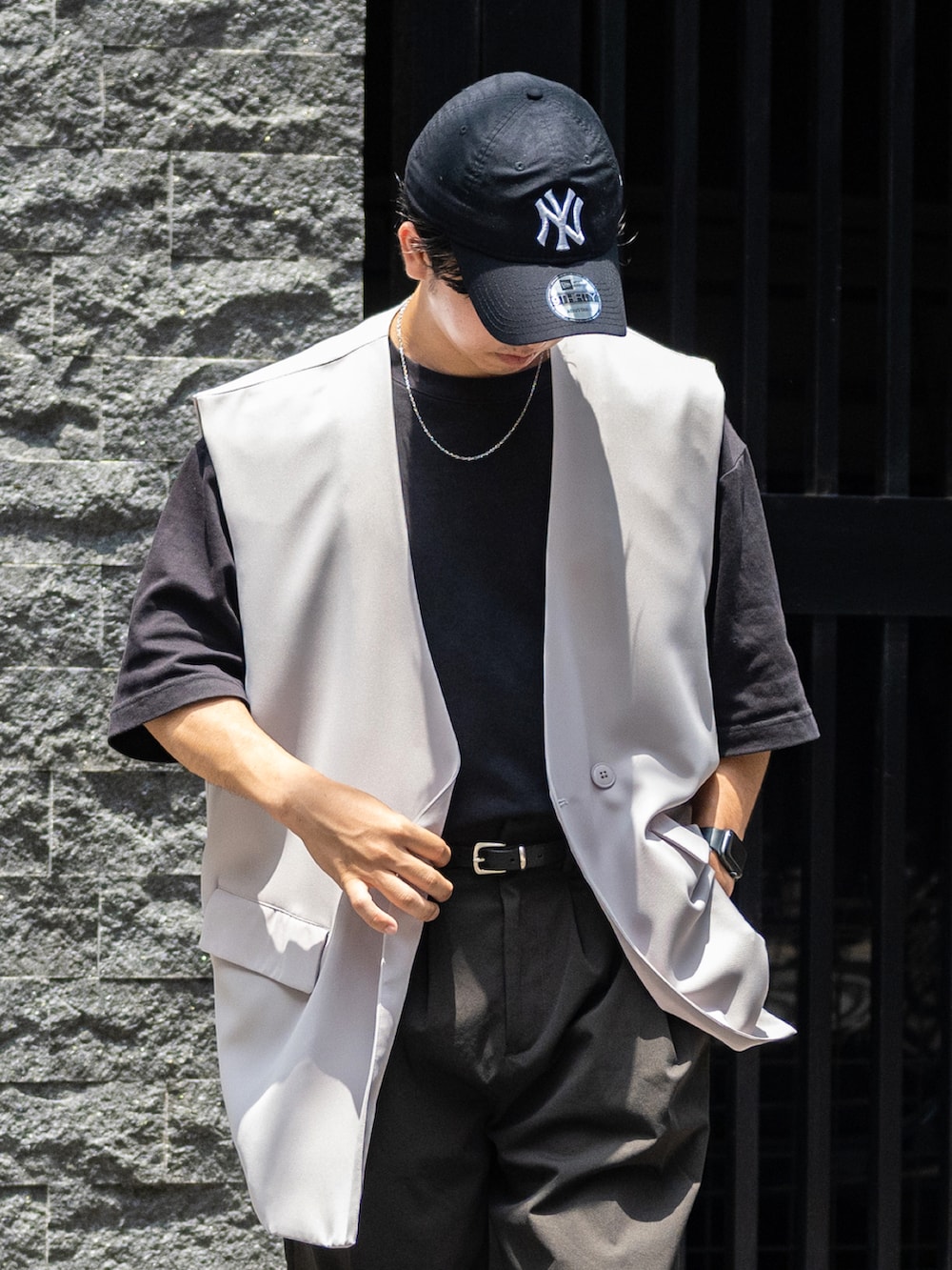 グレー系のスラックス、グリーン系のスニーカー、ブラック系のTシャツ/カットソーを着用したメンズの夏コーディネートの3枚目の写真