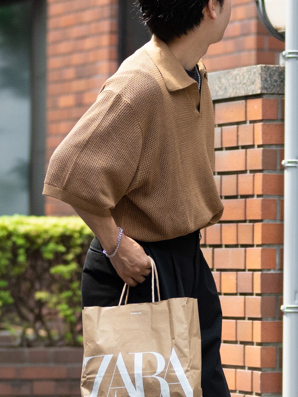 ブラウン系のニット/セーター、ブラック系のスラックス、ブラック系のサンダルを着用したメンズの夏コーディネートの3枚目の写真