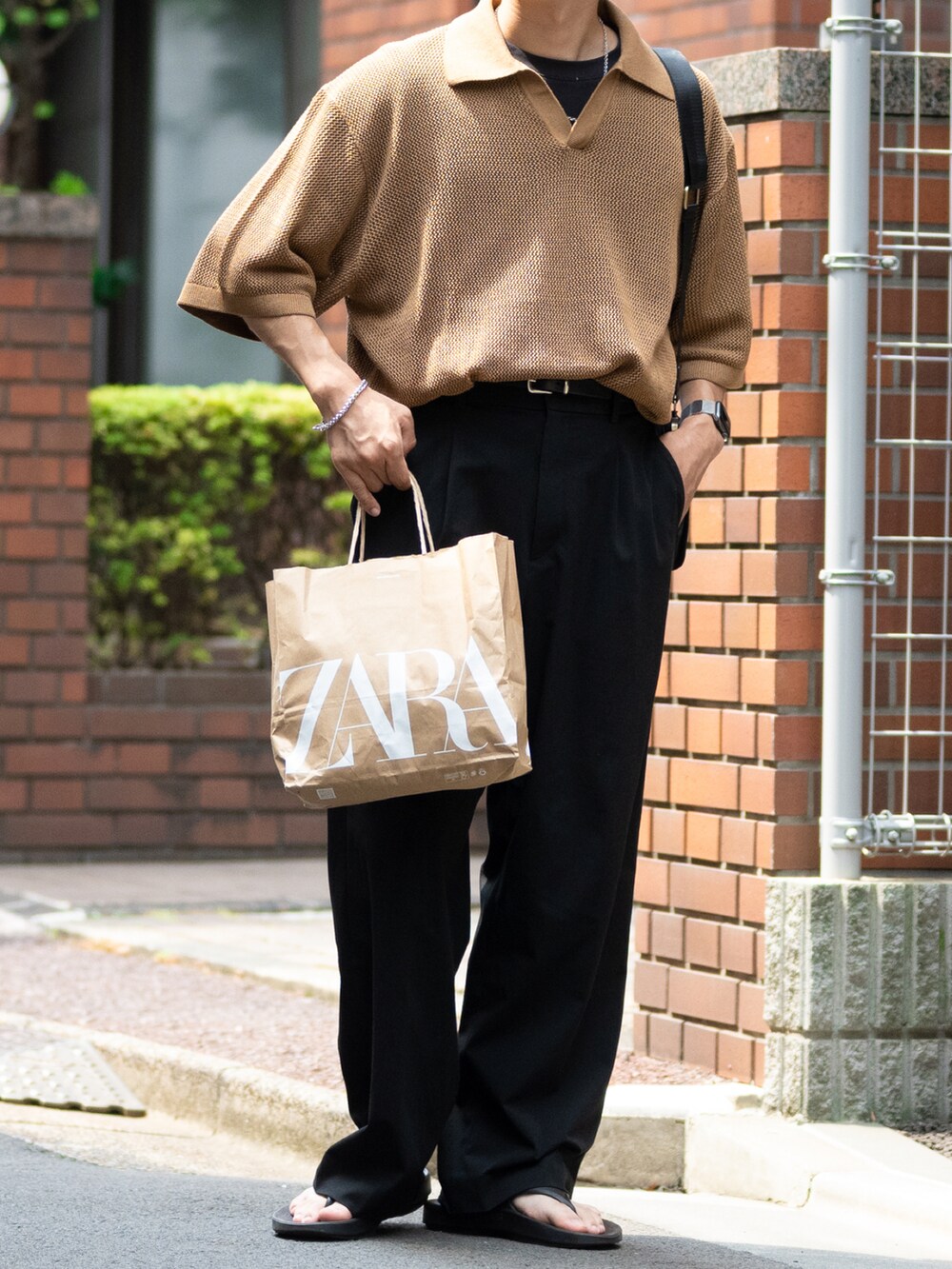 ブラウン系のニット/セーター、ブラック系のスラックス、ブラック系のサンダルを着用したメンズの夏コーディネートの2枚目の写真