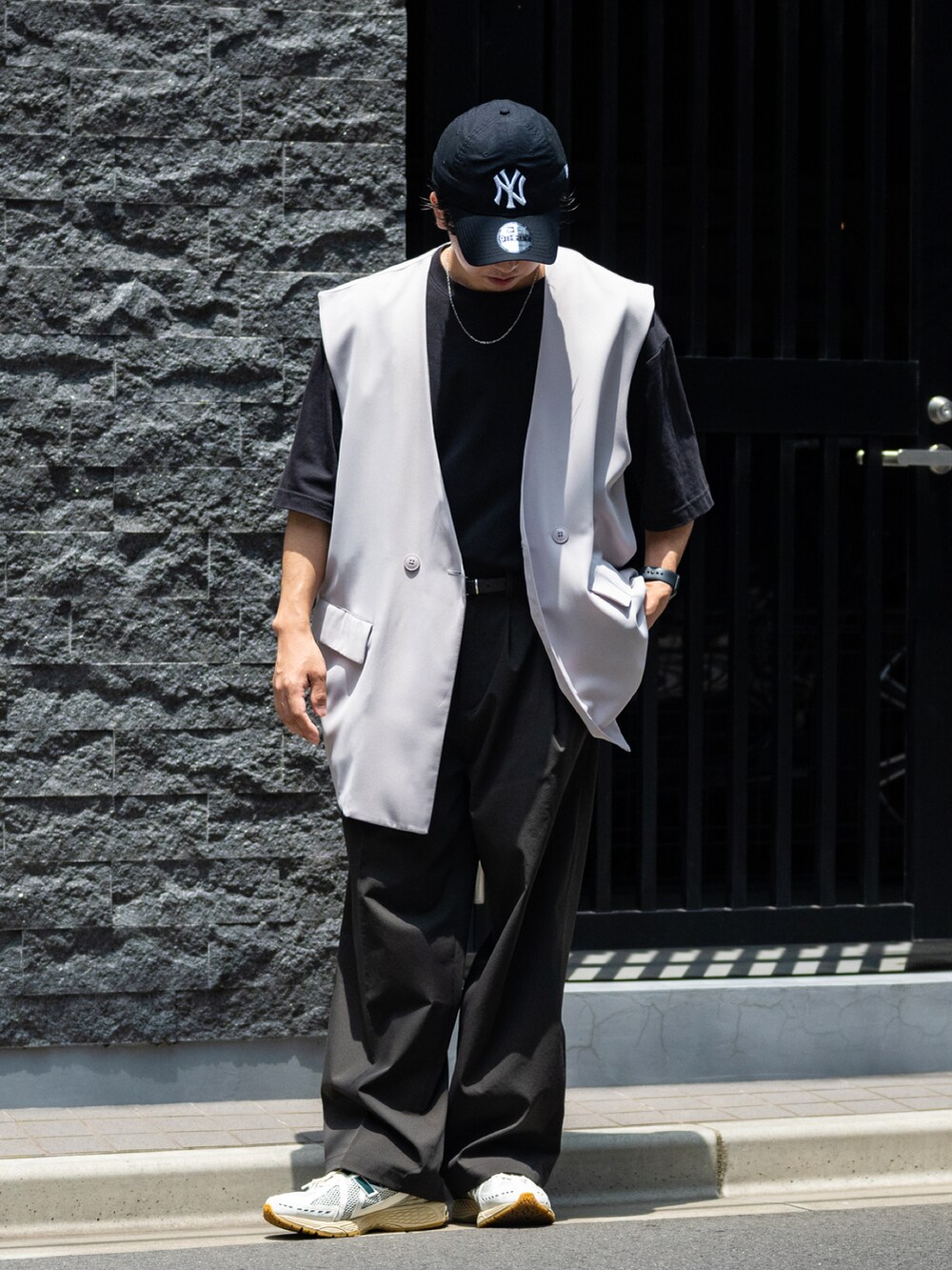 グレー系のスラックス、グリーン系のスニーカー、ブラック系のTシャツ/カットソーを着用したメンズの夏コーディネートの2枚目の写真