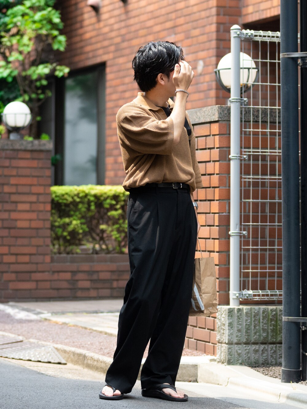 ブラウン系のニット/セーター、ブラック系のスラックス、ブラック系のサンダルを着用したメンズの夏コーディネートの4枚目の写真