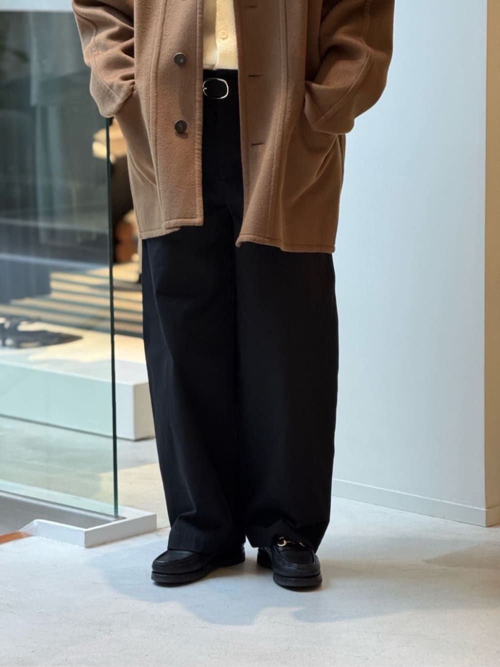 イエロー系のステンカラーコート、ブラック系のその他パンツを着用したメンズの冬コーディネートの2枚目の写真