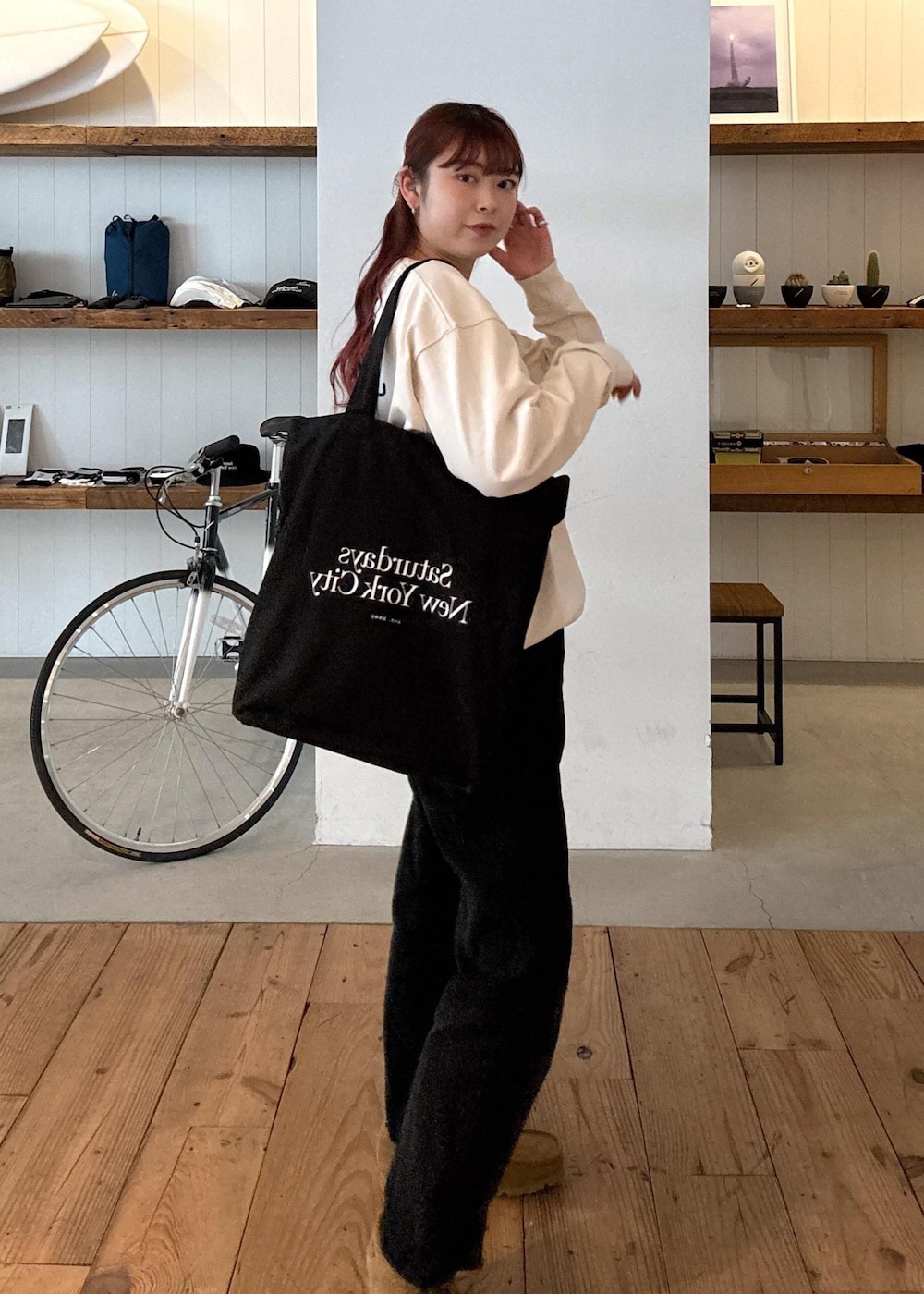 ブラック系のデニムパンツ、ブラック系のトートバッグ、ホワイト系のTシャツ/カットソーを着用したレディースの春コーディネートの2枚目の写真