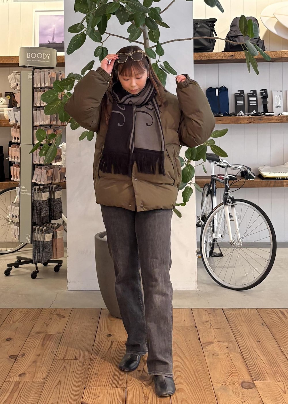 グリーン系のブルゾン、ブラック系のマフラー、ホワイト系のサングラスを着用したレディースの冬コーディネートの2枚目の写真