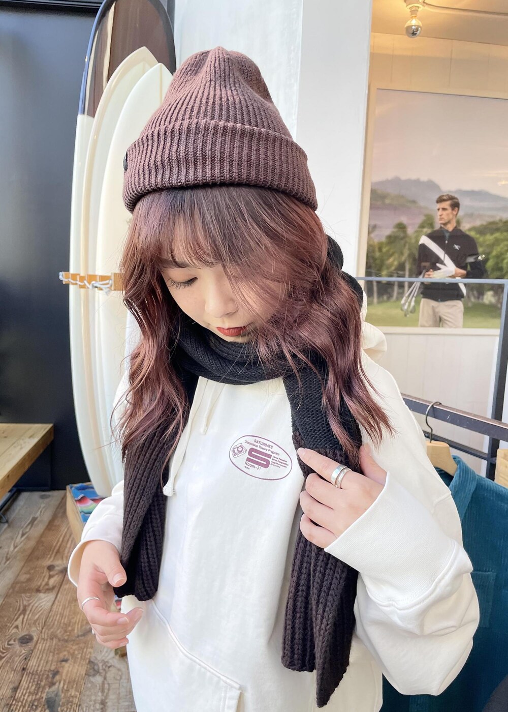 ホワイト系のパーカー、ブラウン系のニットキャップ/ビーニー、ブラック系のマフラーを着用したレディースの冬コーディネートの2枚目の写真