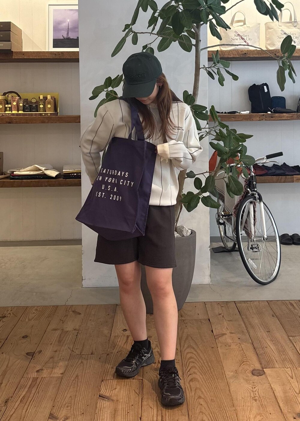 ブラック系のその他パンツ、パープル系のトートバッグ、グリーン系のキャップを着用したレディースの秋コーディネートの3枚目の写真