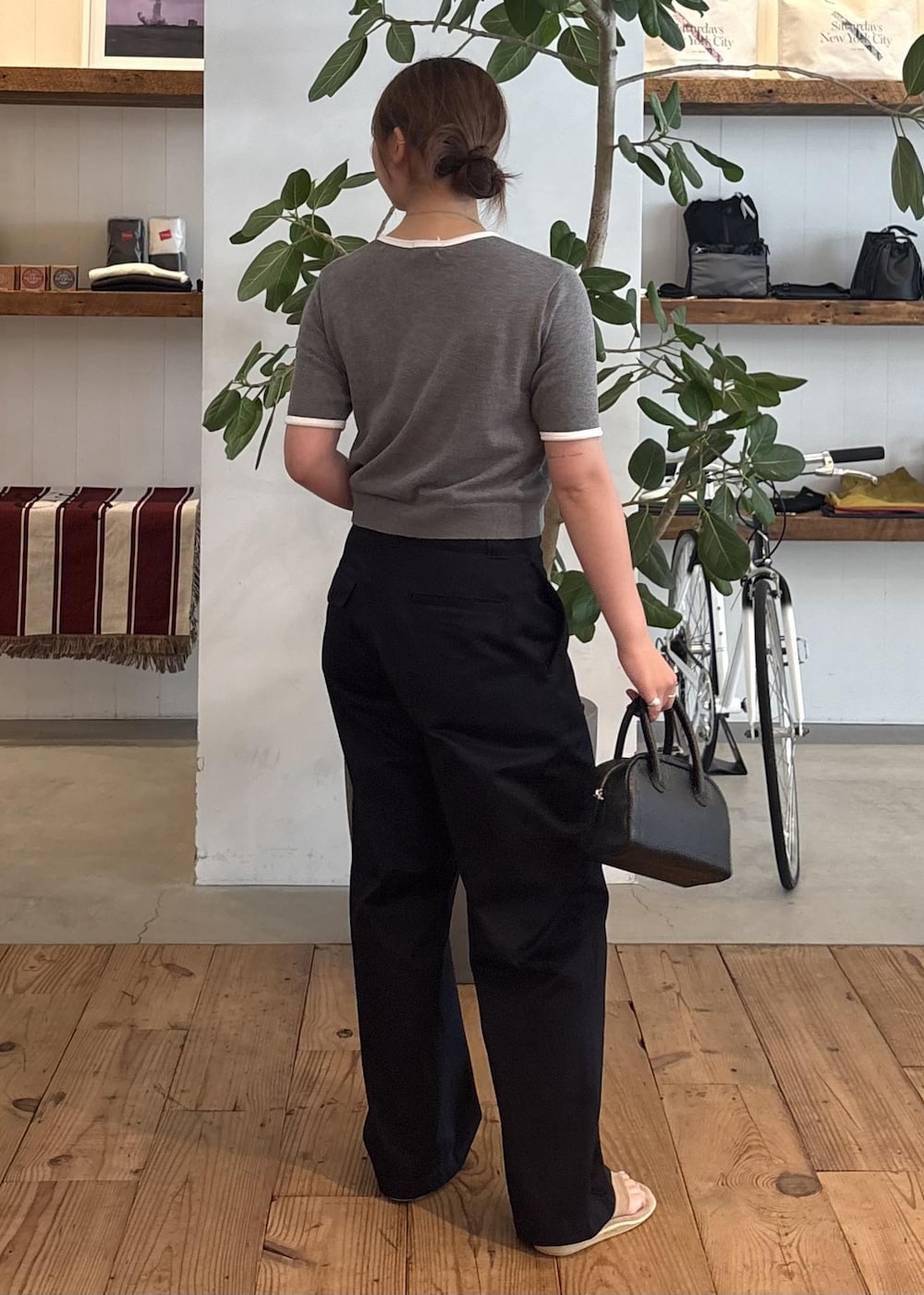 ブラック系のハンドバッグ、ブルー系のチノパンツ、グレー系のTシャツ/カットソーを着用したレディースの夏コーディネートの3枚目の写真