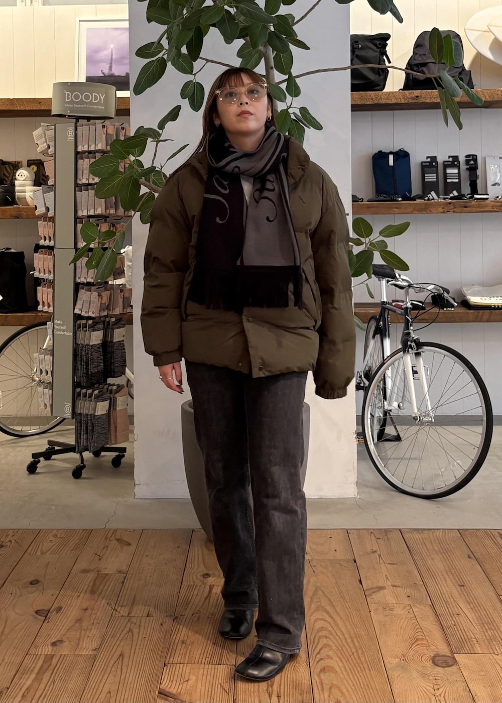 グリーン系のブルゾン、ブラック系のマフラー、ホワイト系のサングラスを着用したレディースの冬コーディネートの3枚目の写真