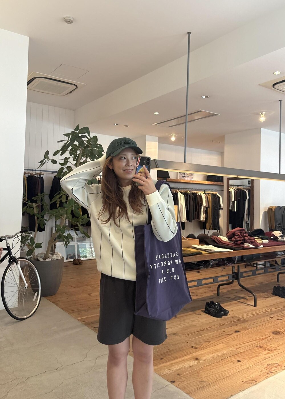 ブラック系のその他パンツ、パープル系のトートバッグ、グリーン系のキャップを着用したレディースの秋コーディネートの4枚目の写真