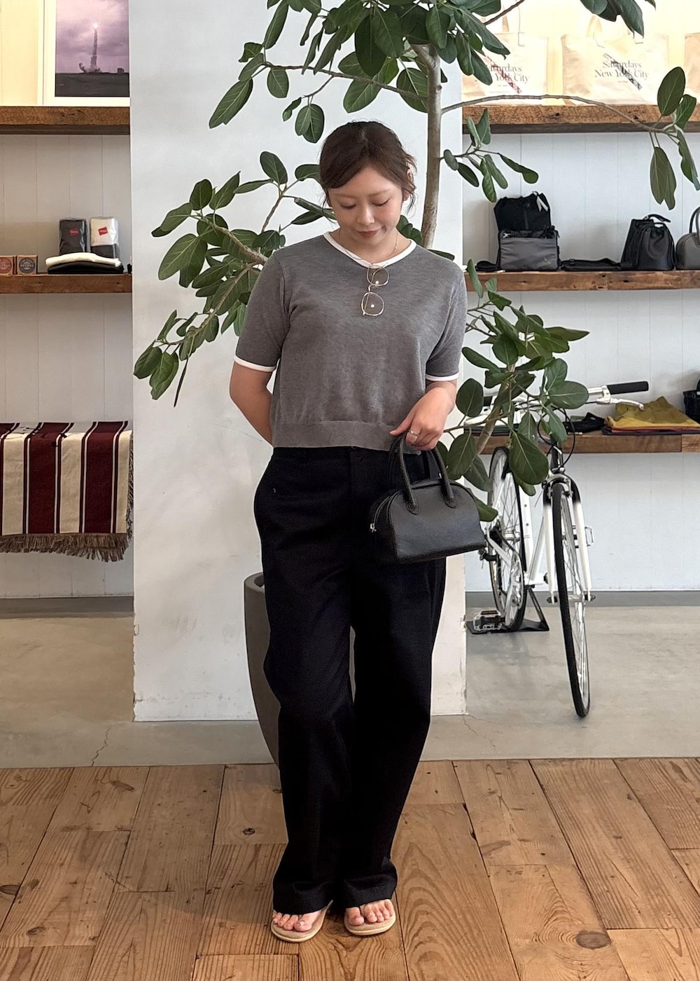 ブラック系のハンドバッグ、ブルー系のチノパンツ、グレー系のTシャツ/カットソーを着用したレディースの夏コーディネートの2枚目の写真