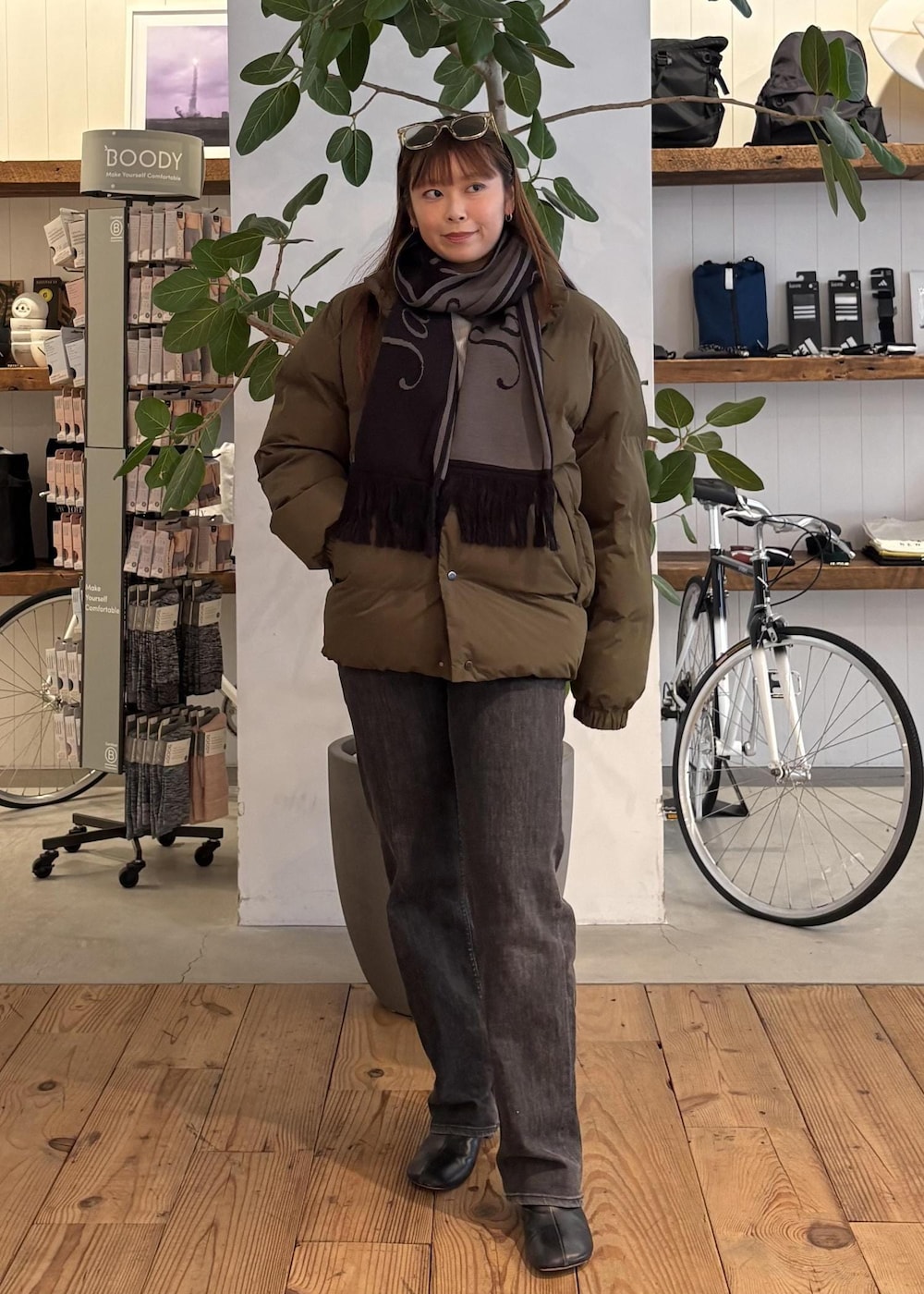 グリーン系のブルゾン、ブラック系のマフラー、ホワイト系のサングラスを着用したレディースの冬コーディネートの6枚目の写真