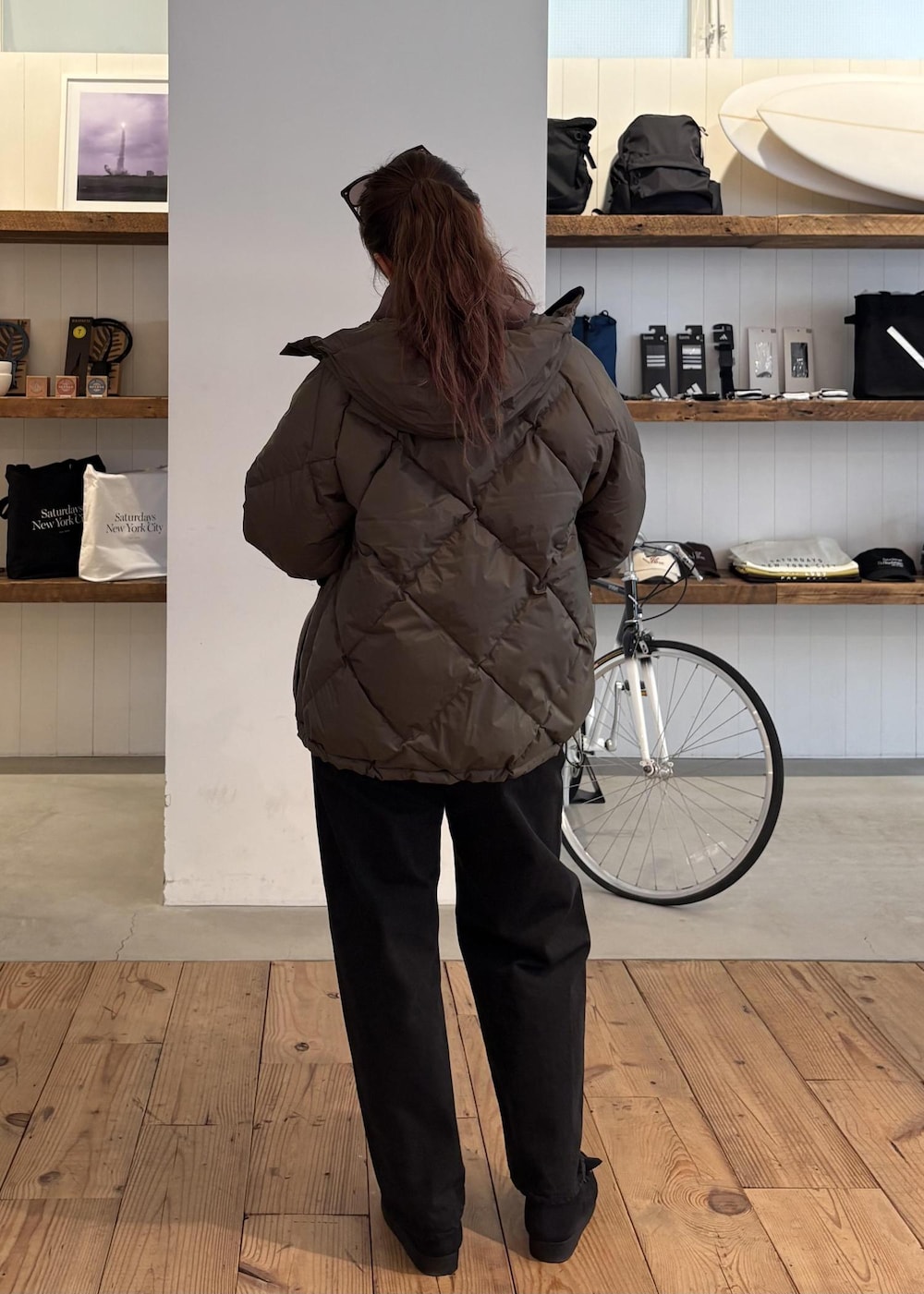 ブラック系のデニムパンツ、グリーン系のダウンジャケット/コート、ブラウン系のパーカーを着用したレディースの冬コーディネートの6枚目の写真