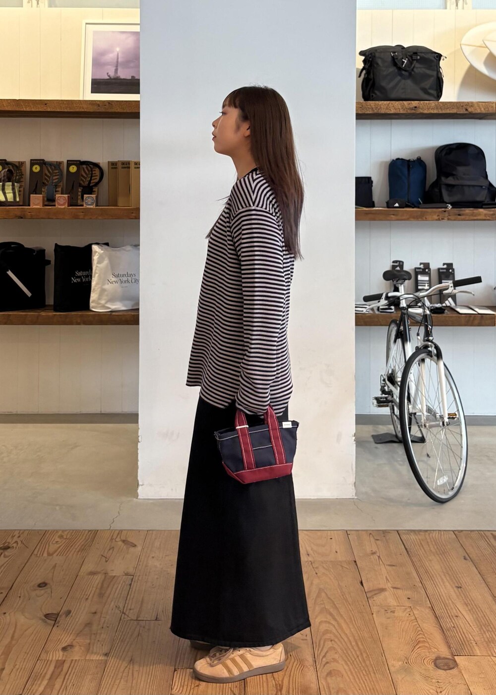 ブルー系のトートバッグ、ブラック系のデニムスカート、グレー系のTシャツ/カットソーを着用したレディースの秋コーディネートの3枚目の写真