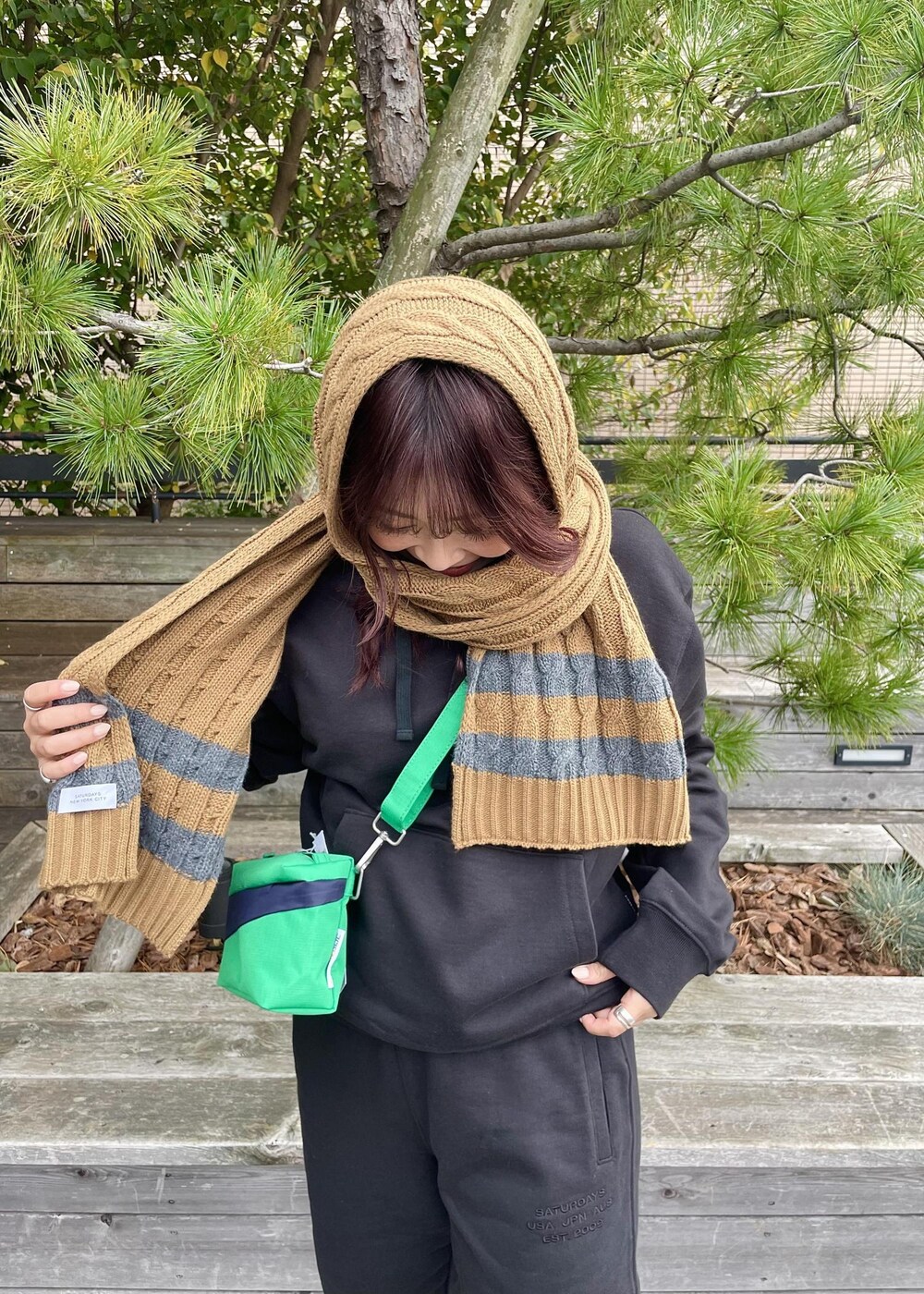 ブラック系のパーカー、ブラック系のスウェットパンツ、イエロー系のマフラーを着用したレディースの秋コーディネートの3枚目の写真